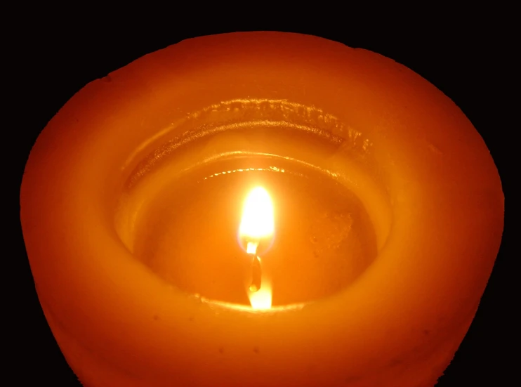 a lit candle sitting in an orange bowl