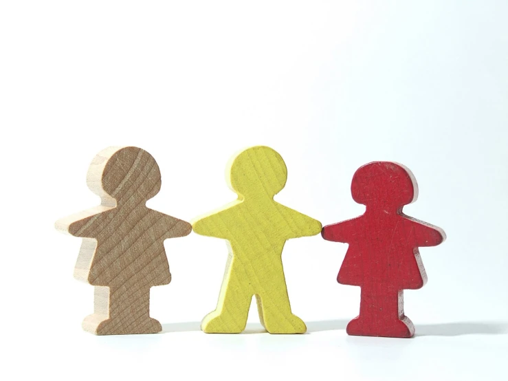 three wooden toy people standing next to each other