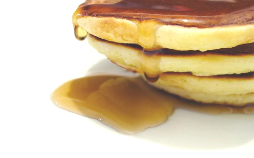 pancakes with syrup being poured on them in the middle