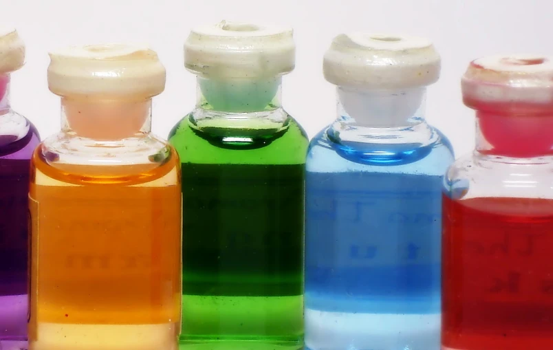 six color liquid bottles are lined up on a table