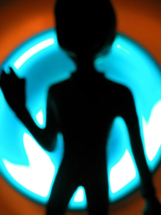 a silhouette s of a person holding up a small cell phone