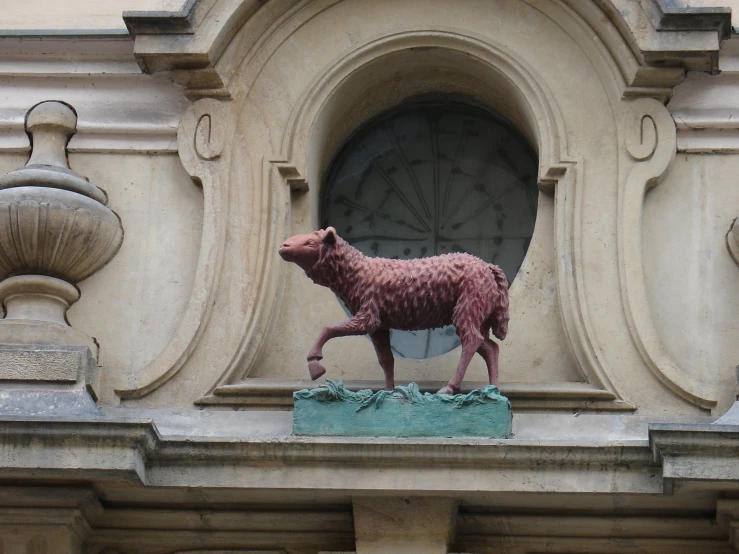 a small statue of a pig stands in front of an ornate window