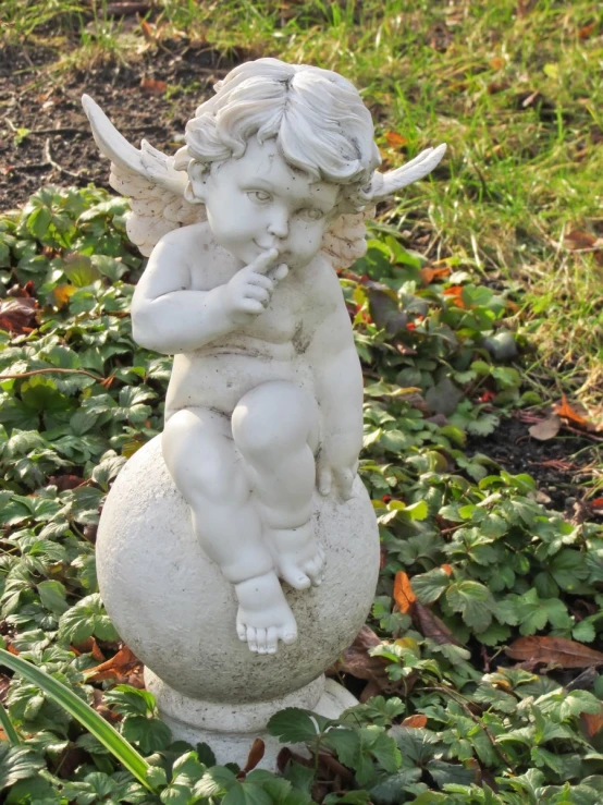 a small white statue of an angel sitting on top of a ball