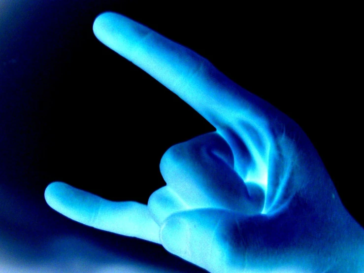 a blue hand holding soing up against a dark background