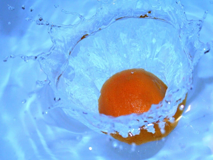 an orange is sitting in water and orange slice has been dropped
