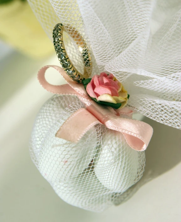 a pink and white flower on a tiny piece of white net