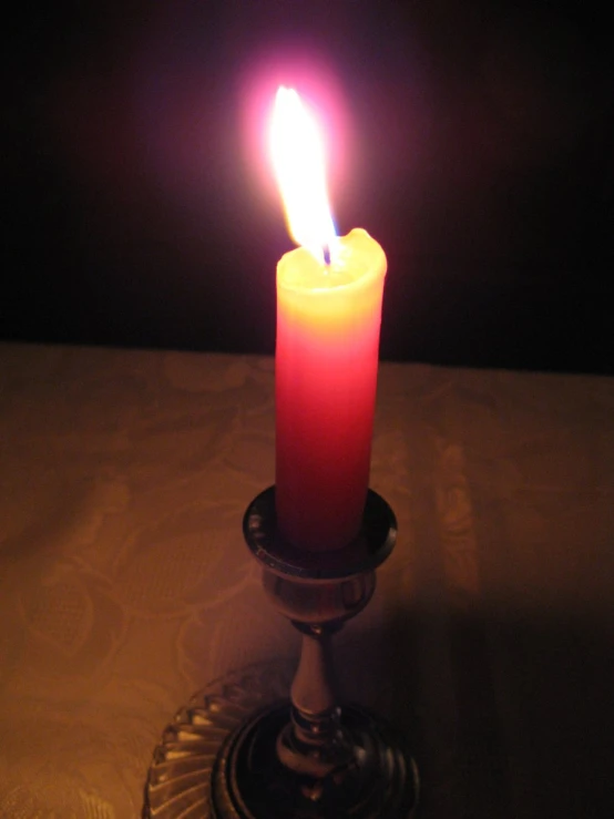 a lit candle on a glass holder with a white background