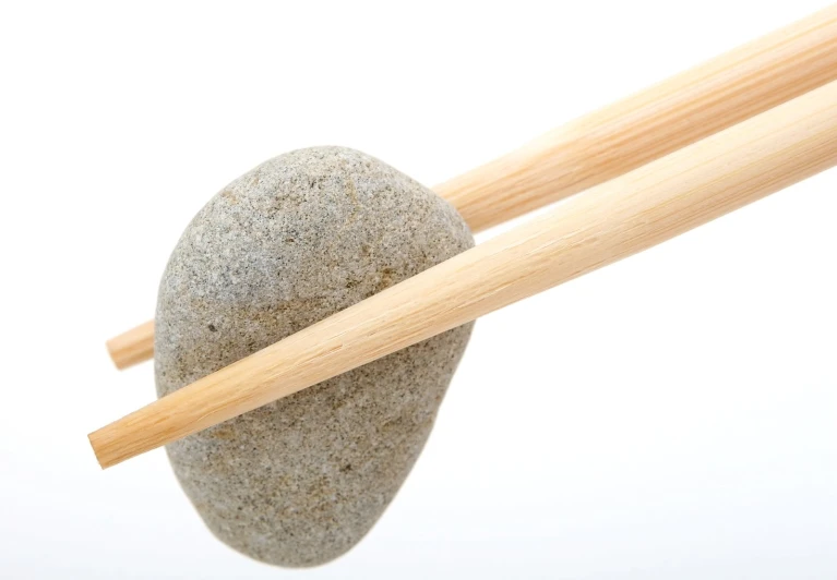 chopsticks resting between a rock and wooden sticks