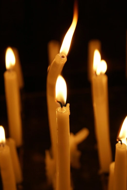 candles are burning in the dark while some are holding candles