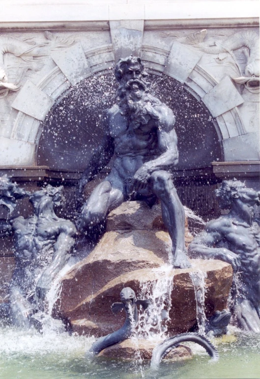 a statue of a man is sitting on a rock next to a fountain