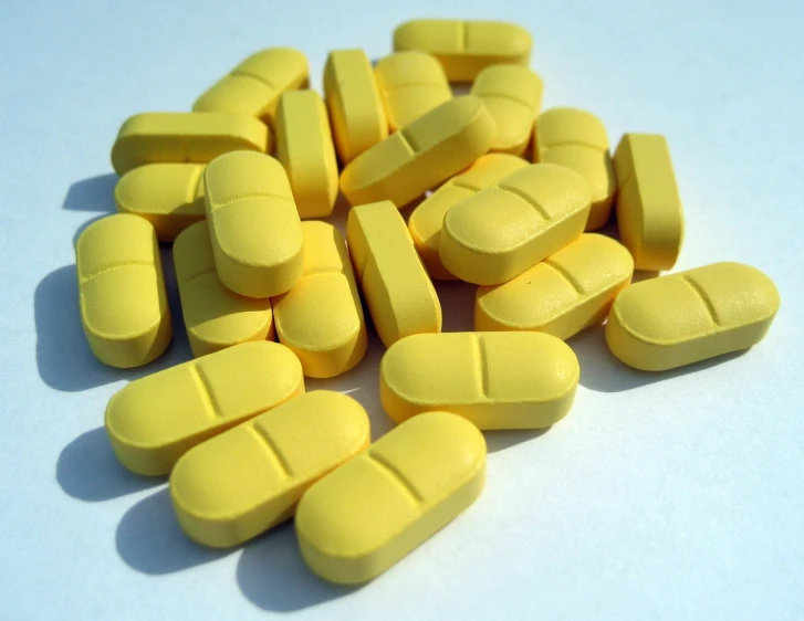 a pile of yellow pills on a white background