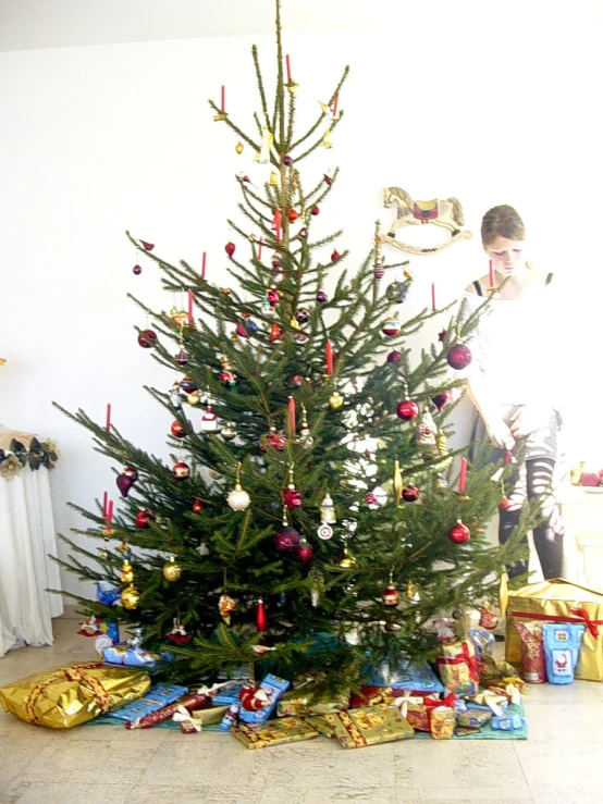 a small boy is standing next to a christmas tree