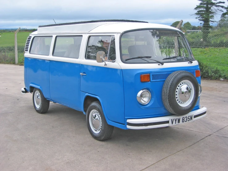 a small blue and white bus parked on a paved lot