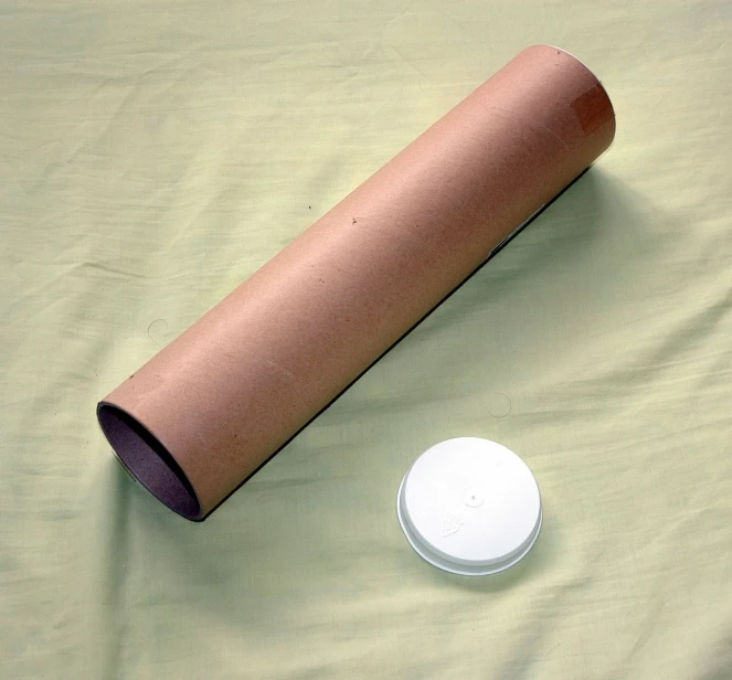 a cylinder next to an electronic device on a table