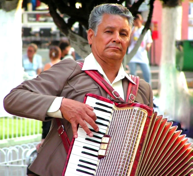 man in tan jacket holding an accordion and posing