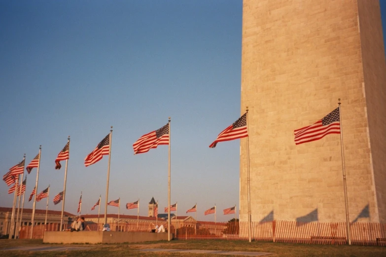 a tall concrete tower sitting in the middle of a field with lots of american flags