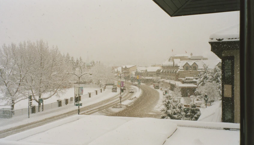 a snow covered street and building with trees and traffic lights