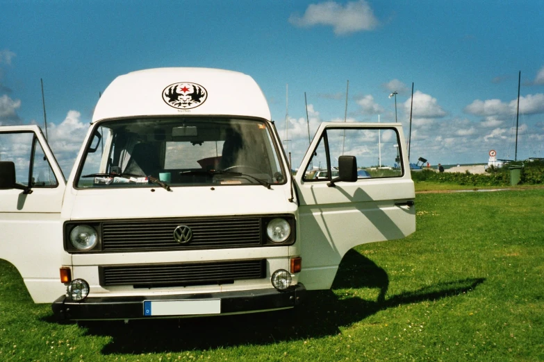 two white vans parked on top of a grass field
