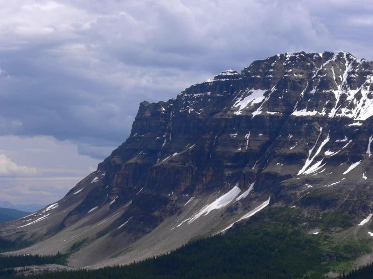 a tall snow covered mountain with clouds above it