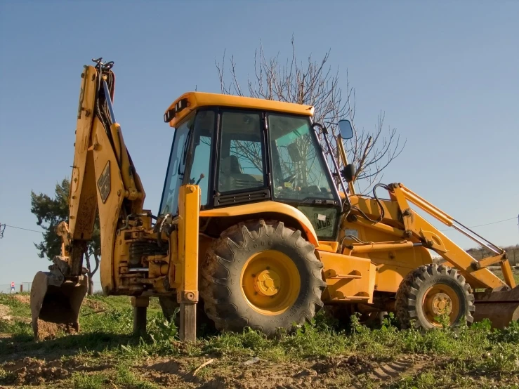 a big yellow tractor next to a pile of leaves