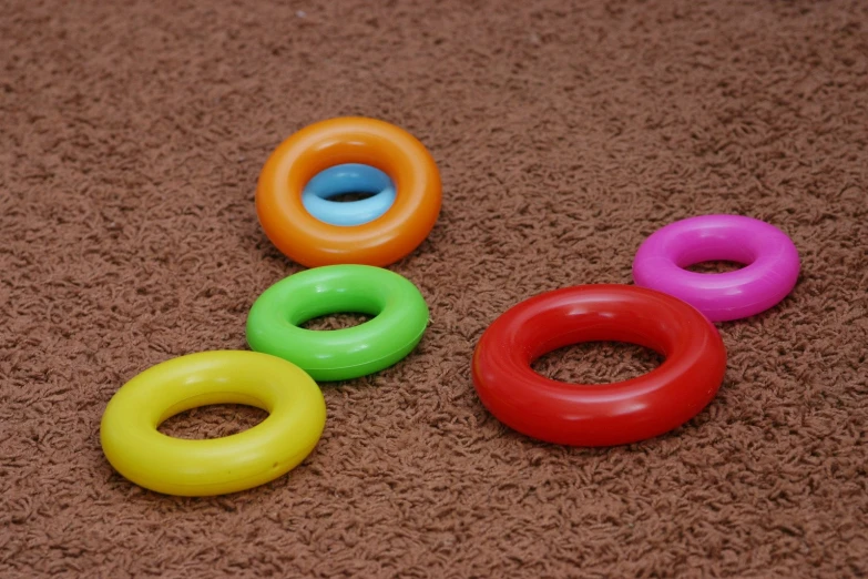five toy rubber rings are shown in several colors