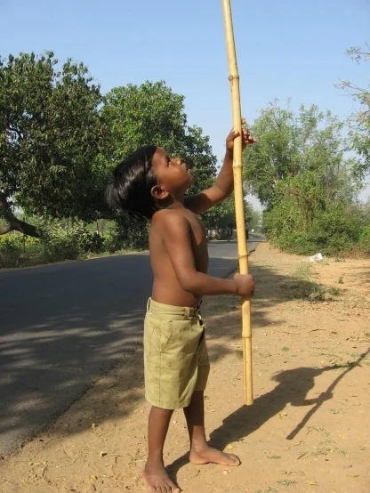 a child is holding onto a pole in the dirt