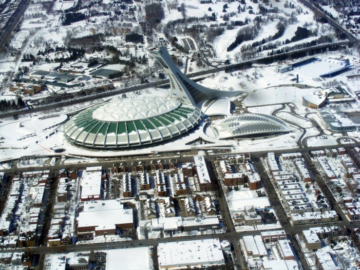 a large stadium building surrounded by snow covered buildings