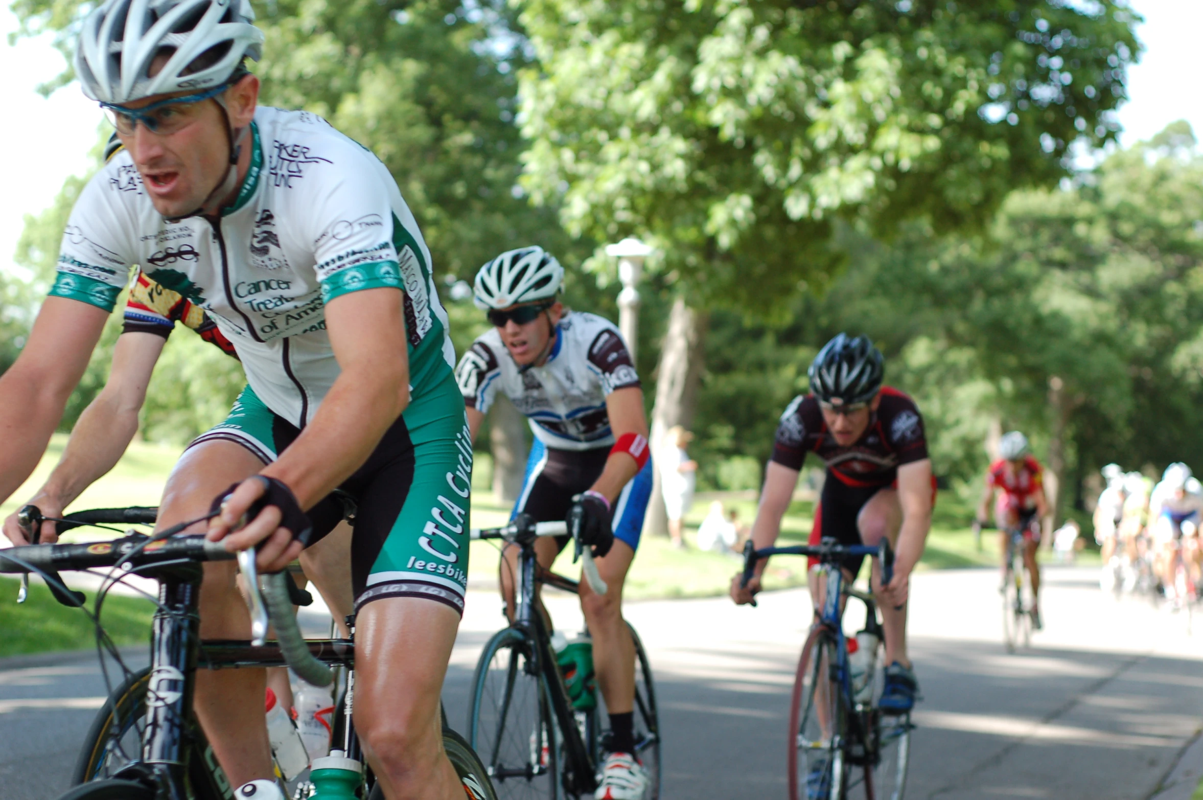 cyclists wearing green and white uniforms ride down the street