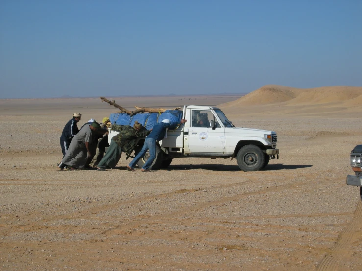 men moving the back end of a truck in the middle of nowhere