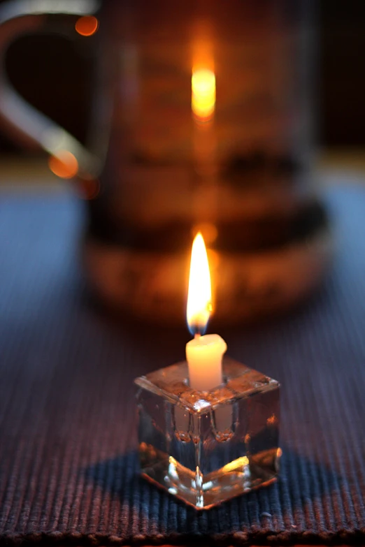 a small candle in the middle of a glass cube