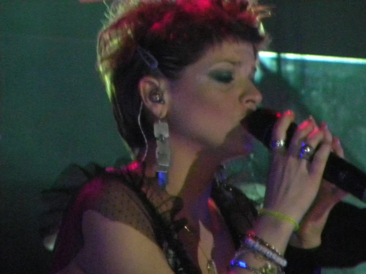 a lady with a short bobb and some jewelry on her head holding a microphone