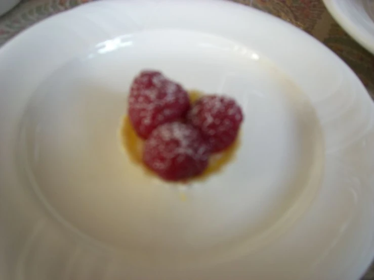 two berries sitting on a white plate covered in jelly