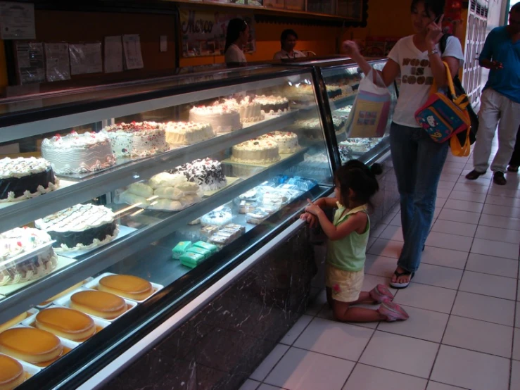 a woman and child reaching to eat some cupcakes