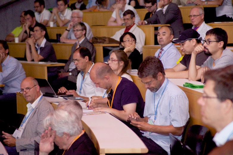 there are many men and women sitting in a lecture hall