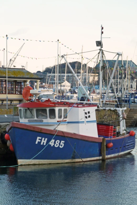 a blue and red boat in the water next to a dock