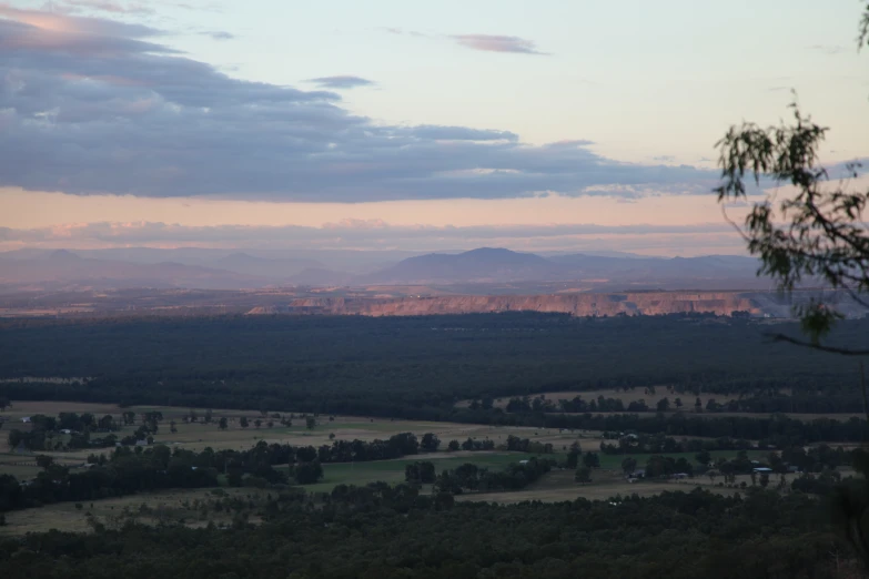 the view from a mountain on the horizon with houses and fields