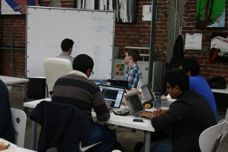 there are men working on computers together at a table