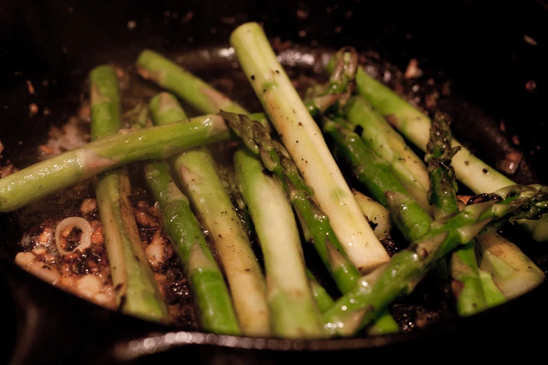 asparagus being cooked with some sauce in a pan