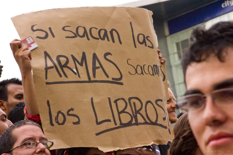 a woman holds a sign in her hand while another man holds a camera