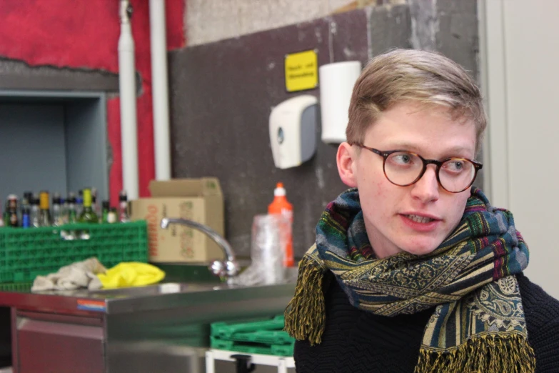 a woman with glasses stands in the kitchen