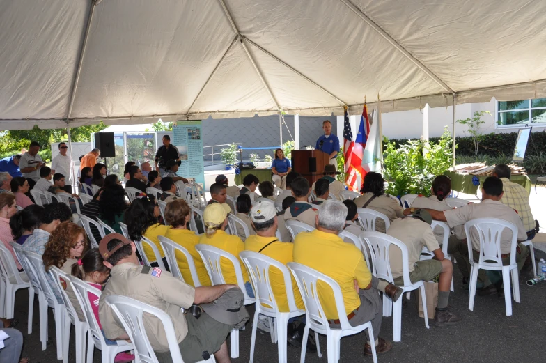 a bunch of people sitting in chairs in a large tent