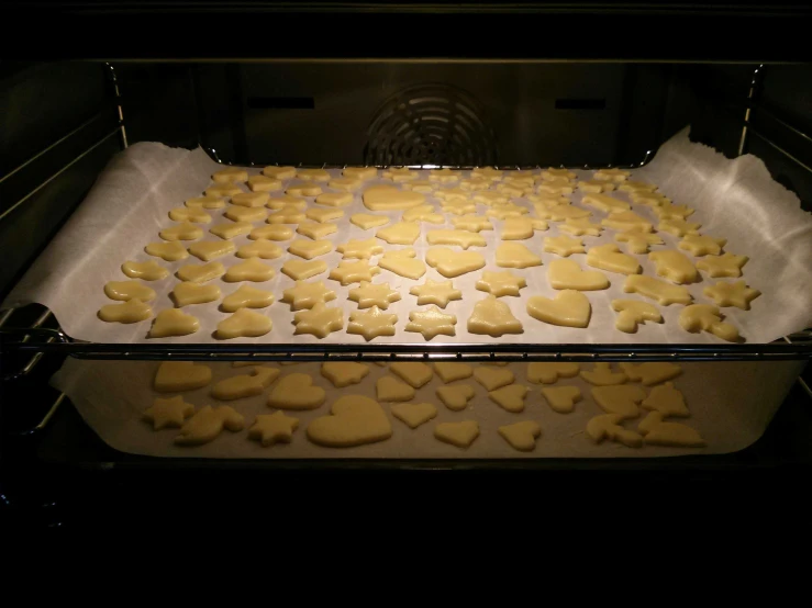 two pans of dough with cut out hearts in it