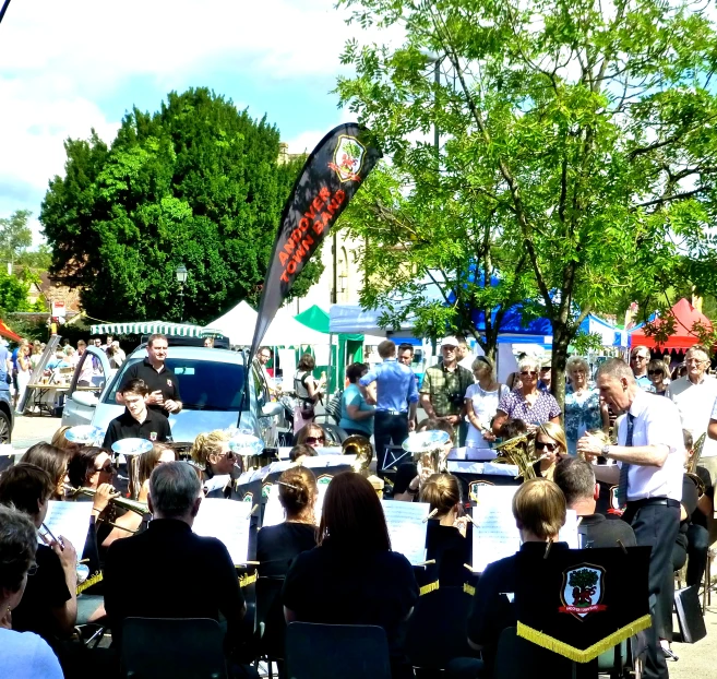 people sitting at tables in the middle of a street watching music