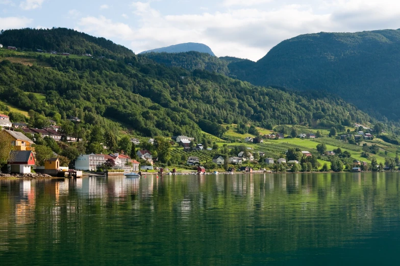 houses and boats on a lake surrounded by mountains