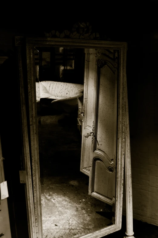 an old, rectangular wooden frame mirror with the door in it's corner