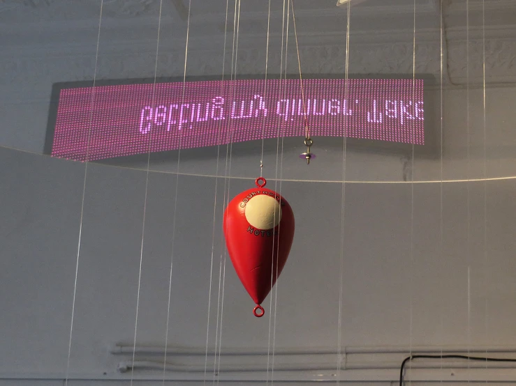 a red clock hanging from the ceiling next to a purple sign