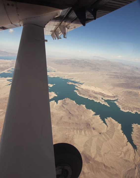 an aerial view from the wing of a plane of mountains and water