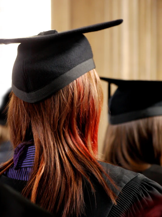 a woman in a graduation cap sitting at the end of a row of other graduates