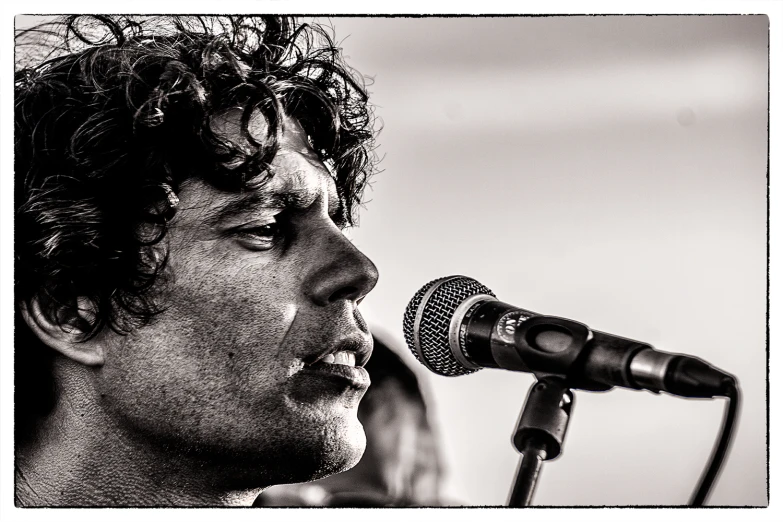 a man with curly hair singing into a microphone