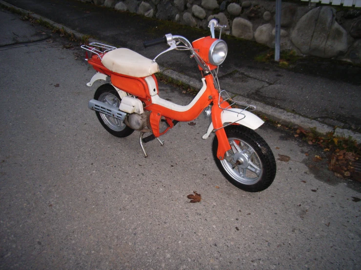 an orange and white scooter parked on the side of a road
